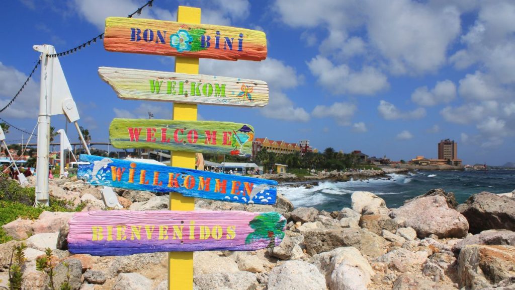 languages spoken in curacao include papiamento, dutch, spanish, english, and german. Here is a sign with all the different languages. 